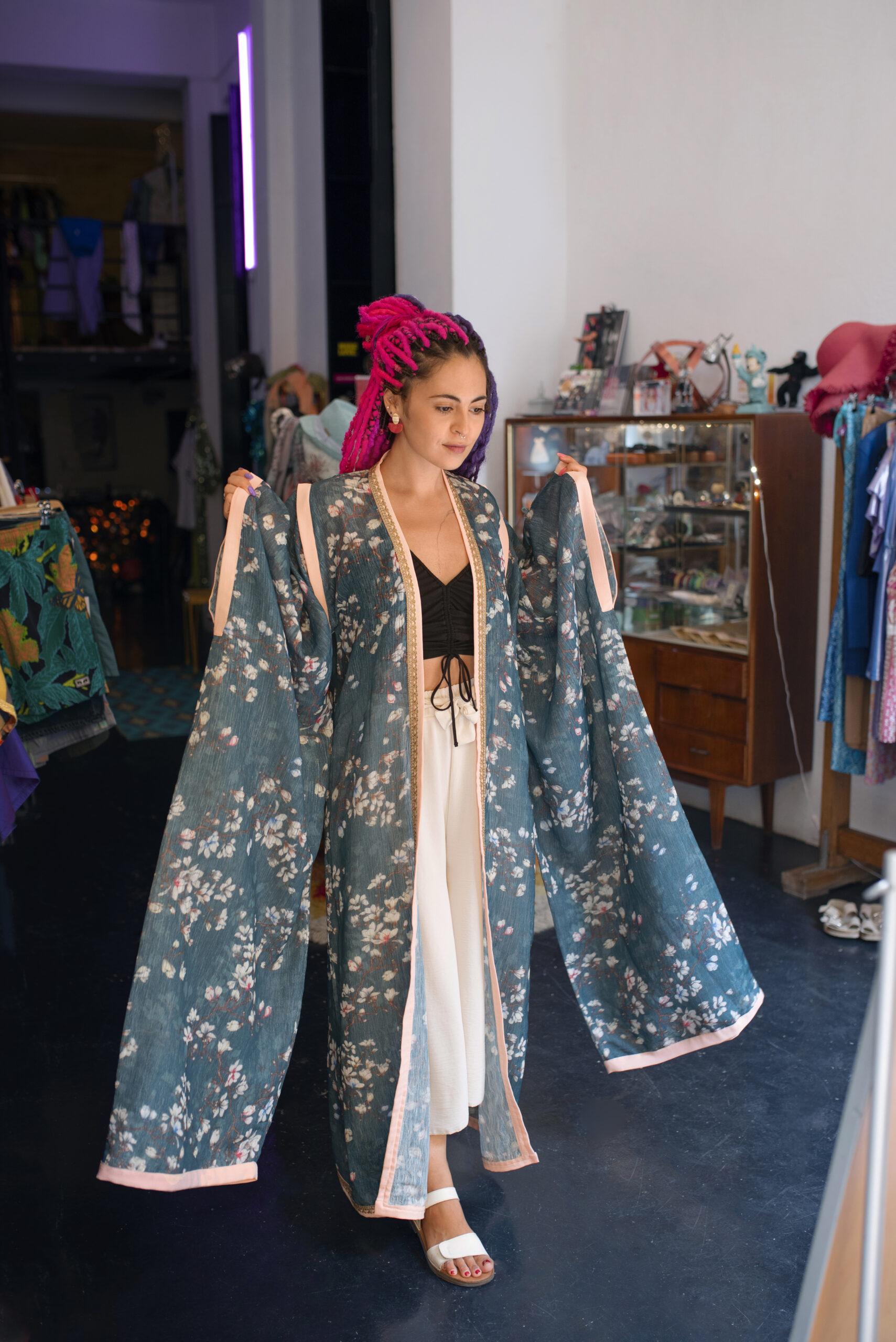 Person trying on a modern kimono-style jacket in a contemporary boutique