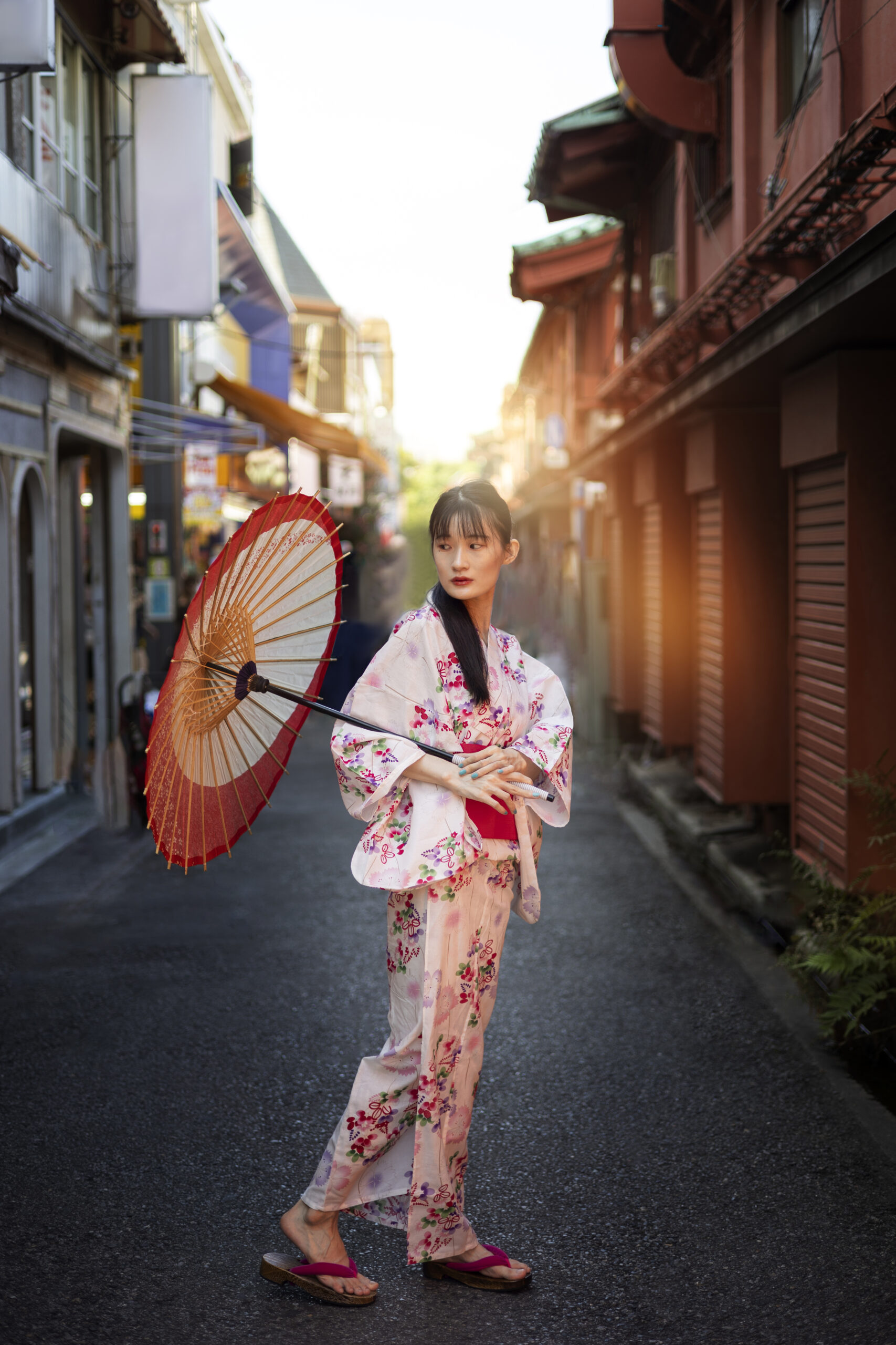 Three women wearing colorful yukatas standing beneath blooming pink cherry blossoms