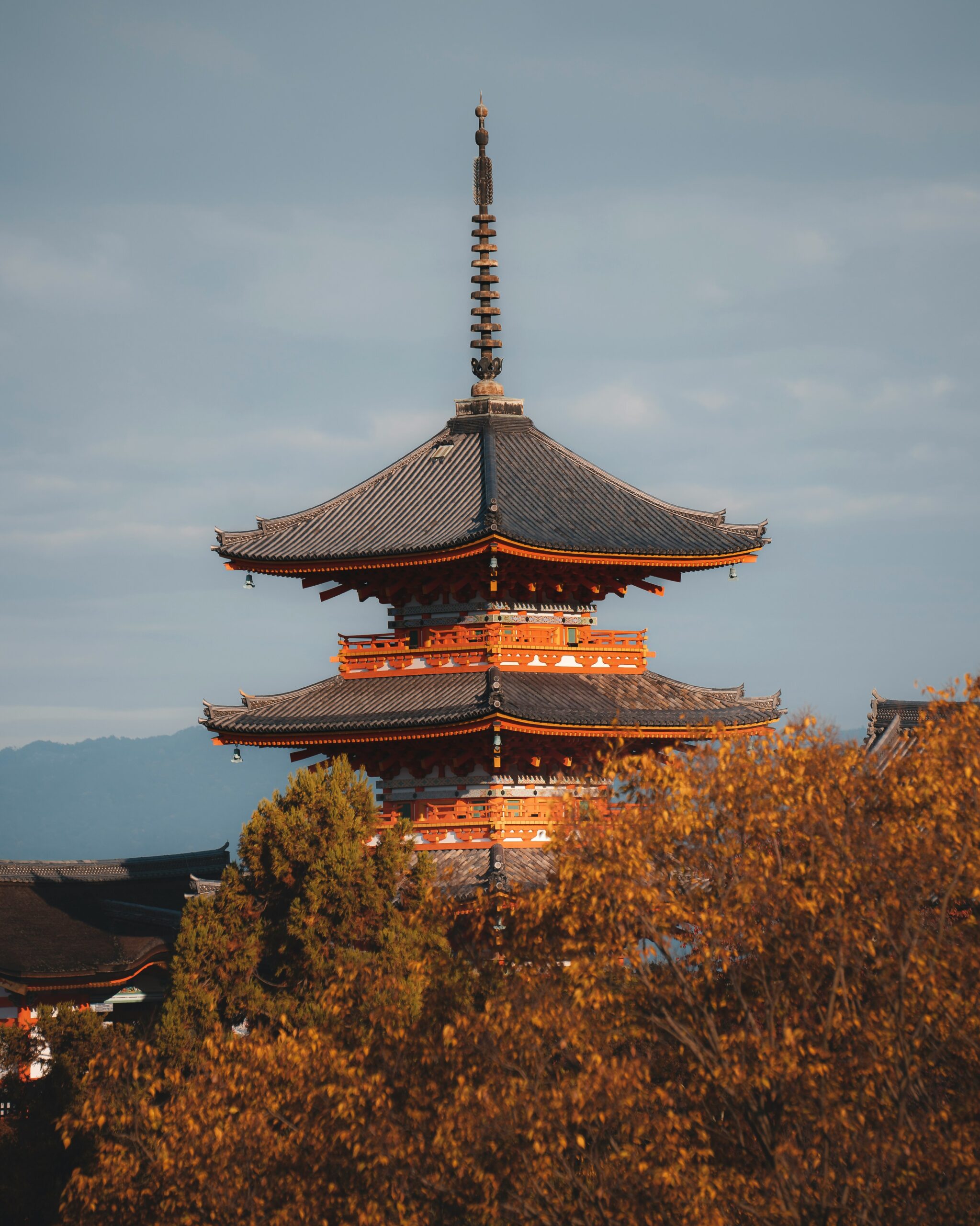 Traditional Japanese pagoda in autumn with orange-colored trees in the foreground