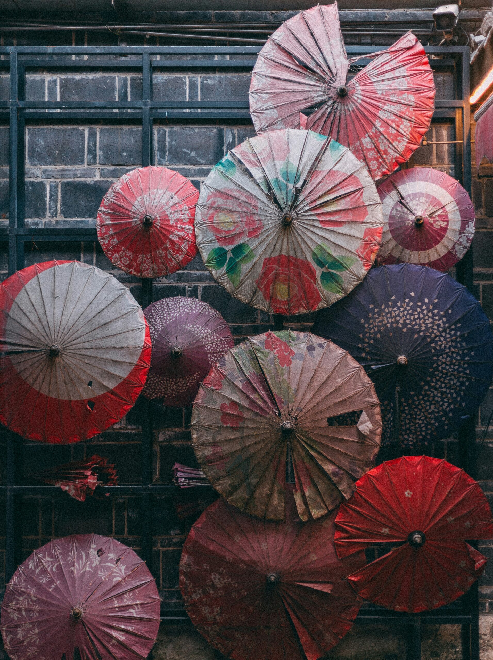 Colorful display of traditional Japanese paper umbrellas in various patterns including floral designs, geometric prints, and solid colors arranged artistically for cultural photography
