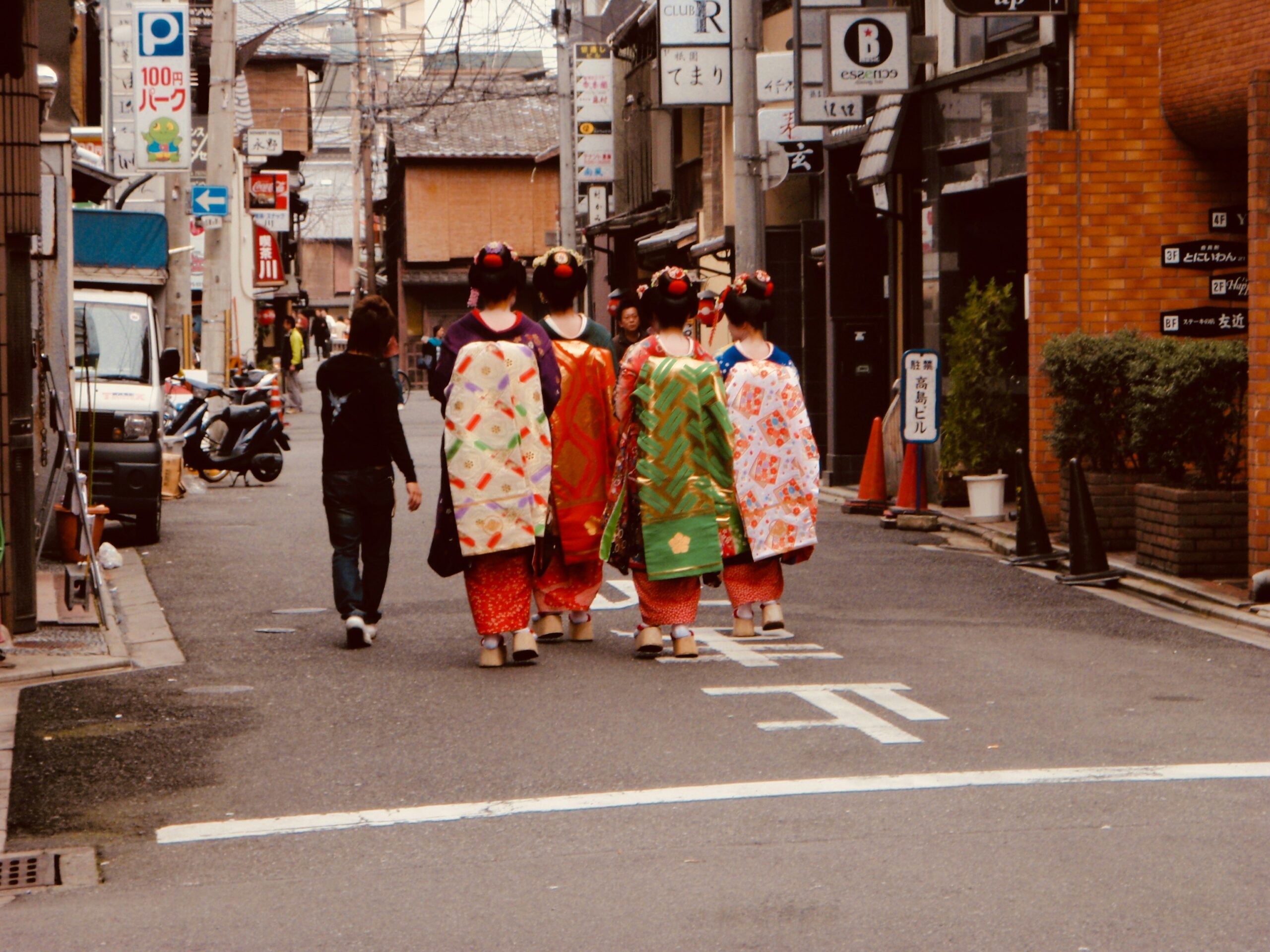 Traditional Japanese maiko and geisha walking through historic Kyoto streets in colorful kimono, showcasing authentic cultural dress experience