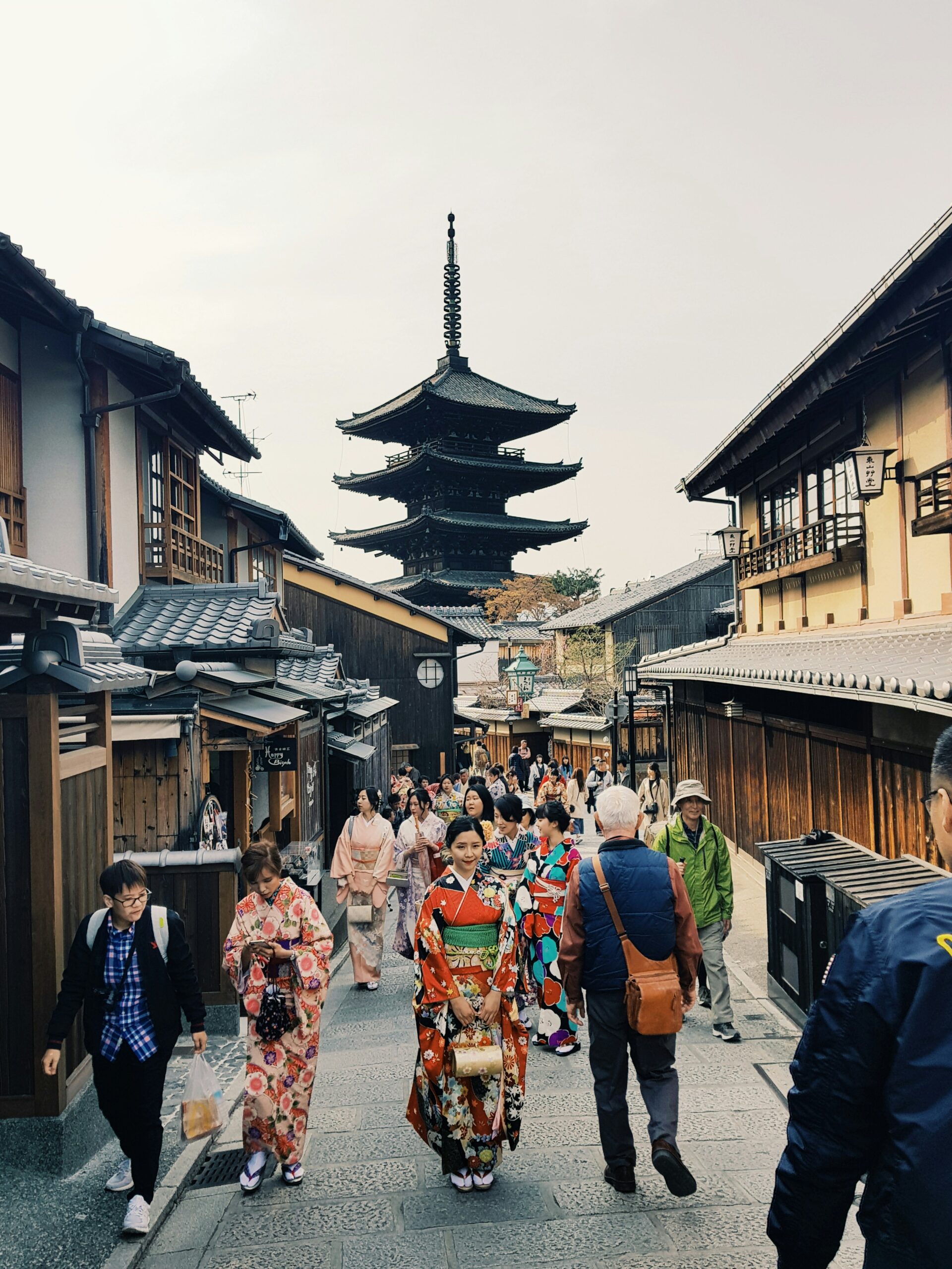京都传统街景，身着色彩鲜艳和服的女性走过五层宝塔，展示经典的和服摄影构图