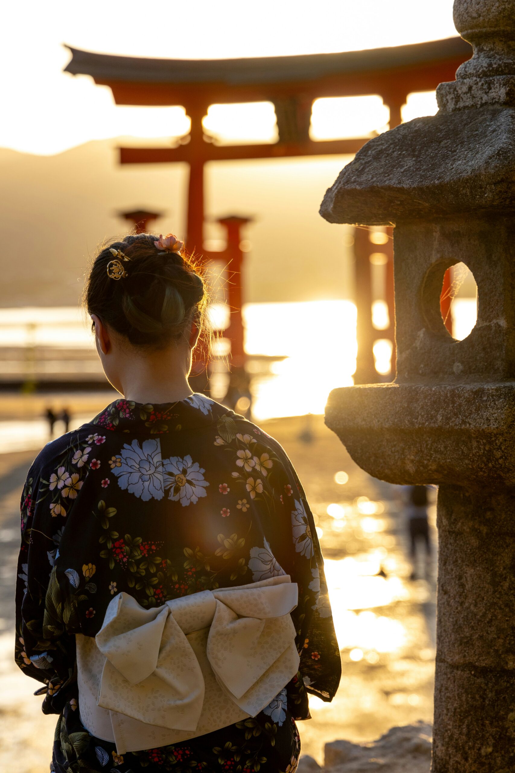 Young Maiko apprentice in vibrant traditional kimono with elaborate hairstyle and colorful accessories walking through Gion district in Kyoto