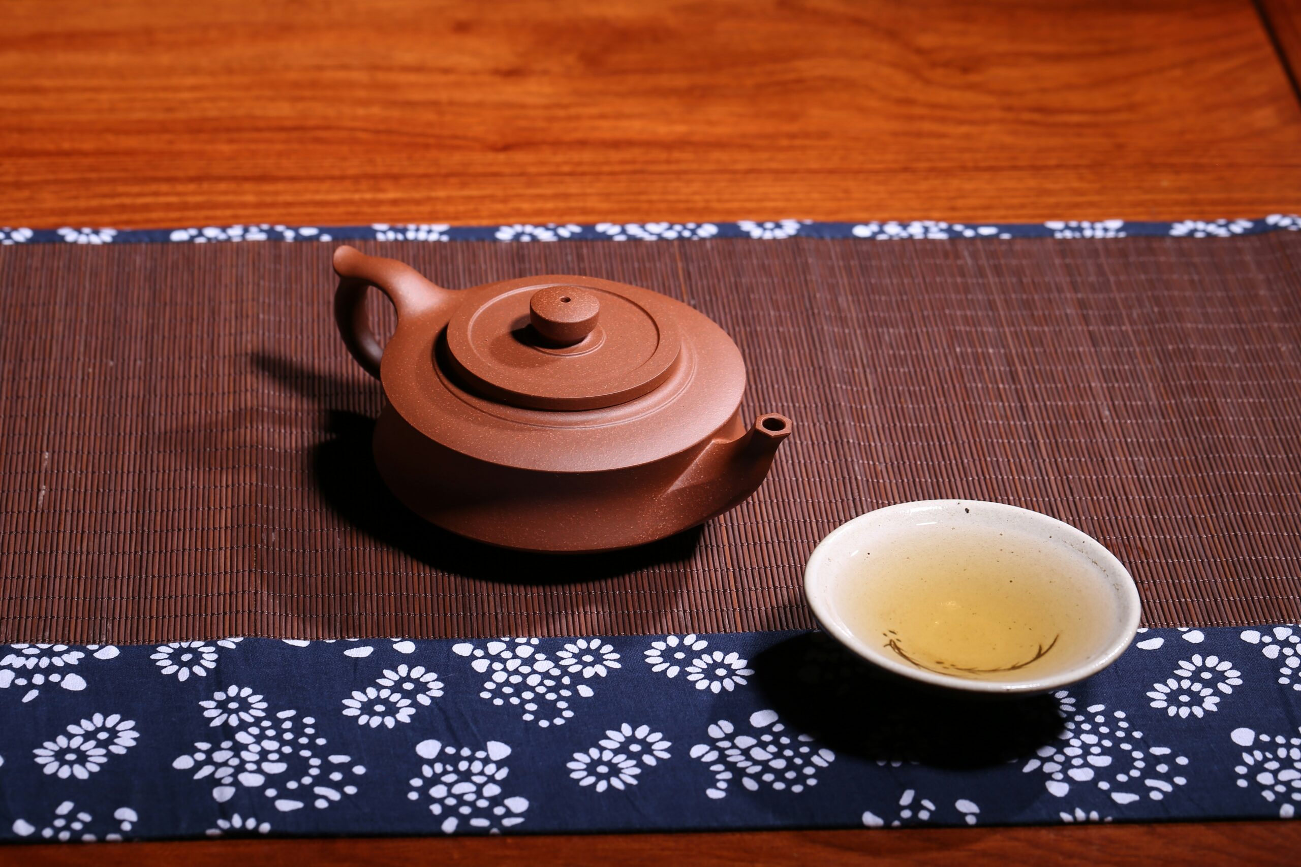 Traditional Japanese tea ceremony setup with clay teapot and tea bowl on woven mat, representing authentic cultural experiences