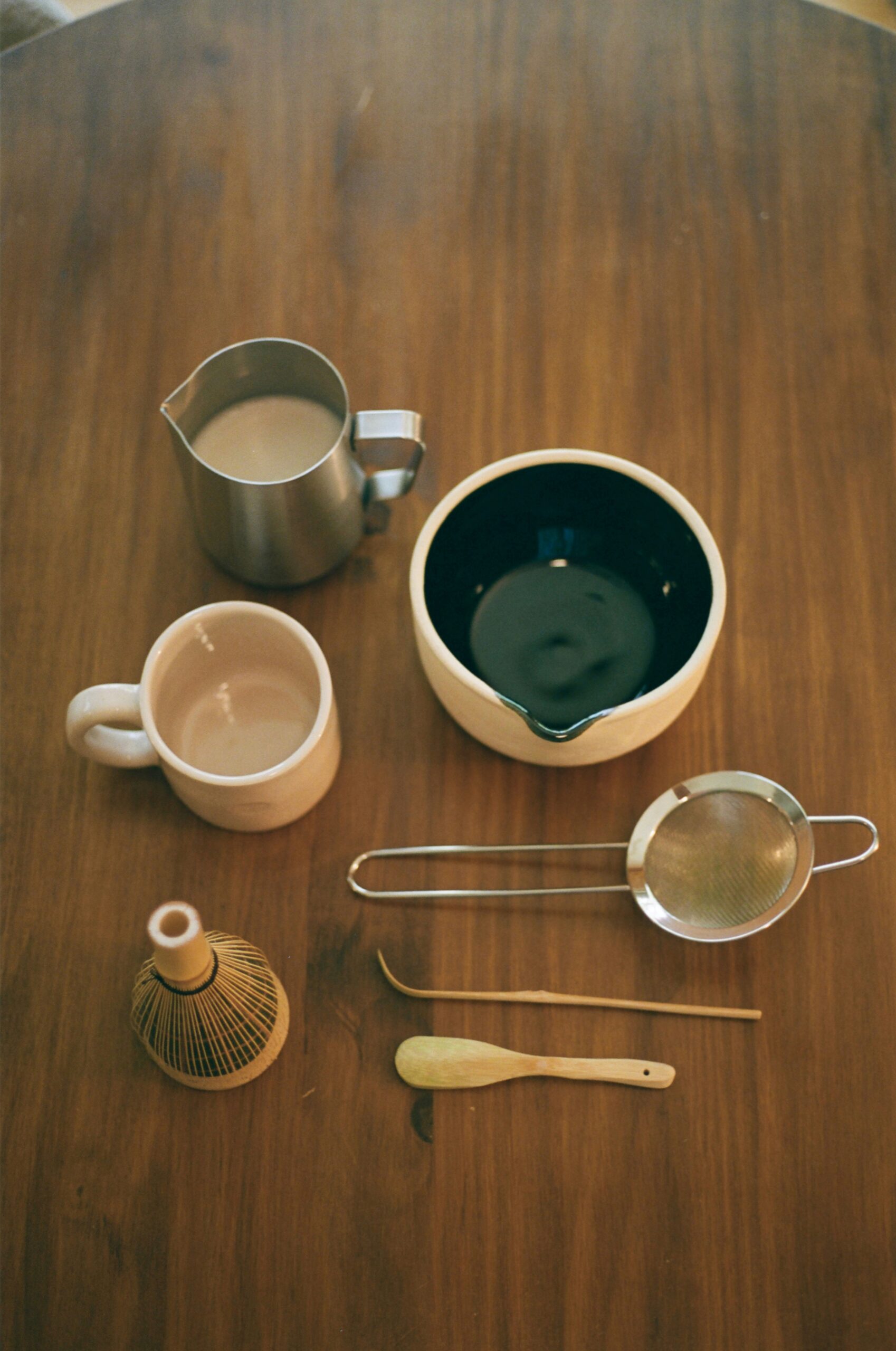Traditional Japanese tea ceremony utensils including chawan bowl, chasen whisk, and chashaku scoop arranged on wooden surface