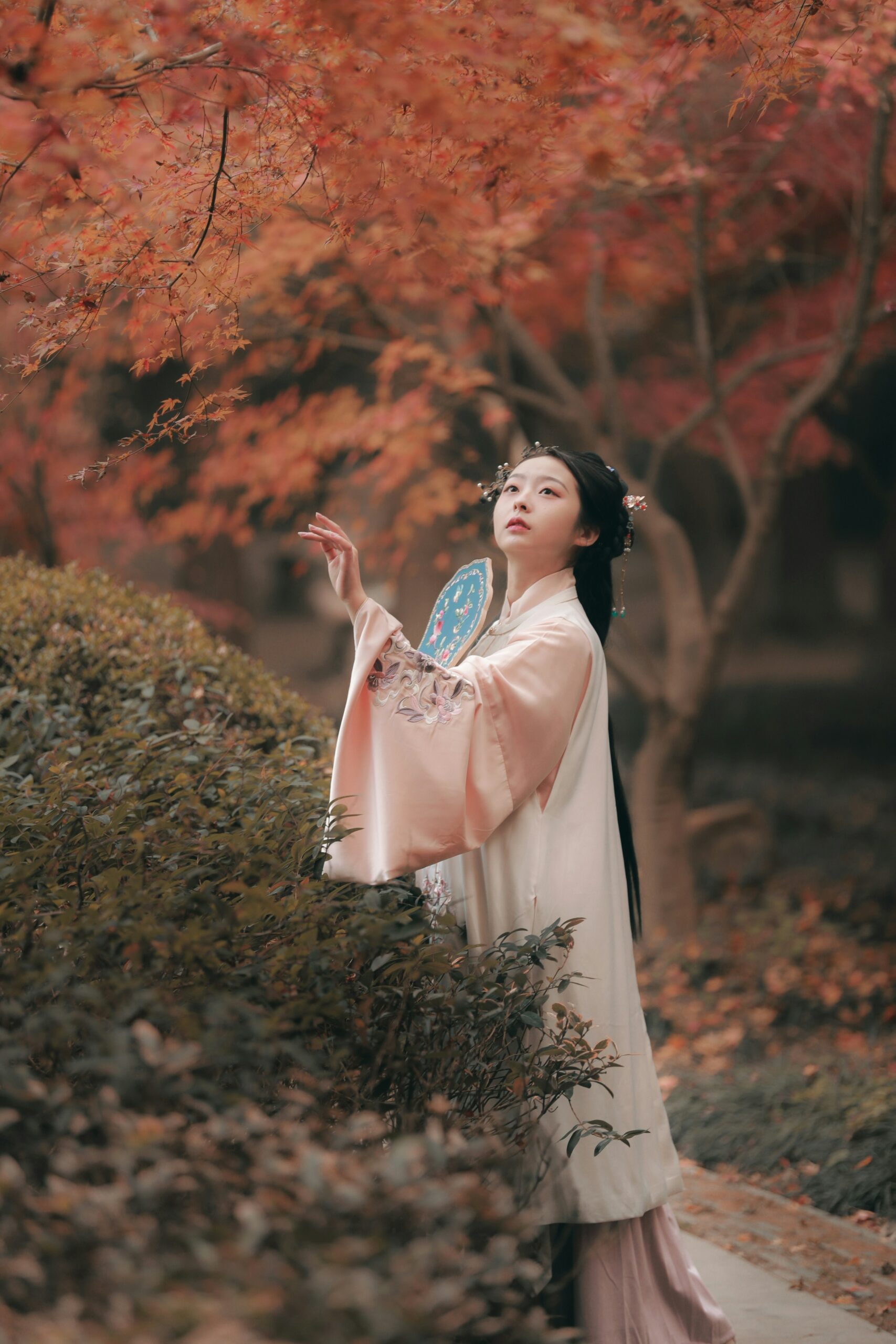 Young Japanese woman in traditional autumn kimono standing at Daigo-ji Temple surrounded by vibrant red maple leaves in Kyoto during fall season