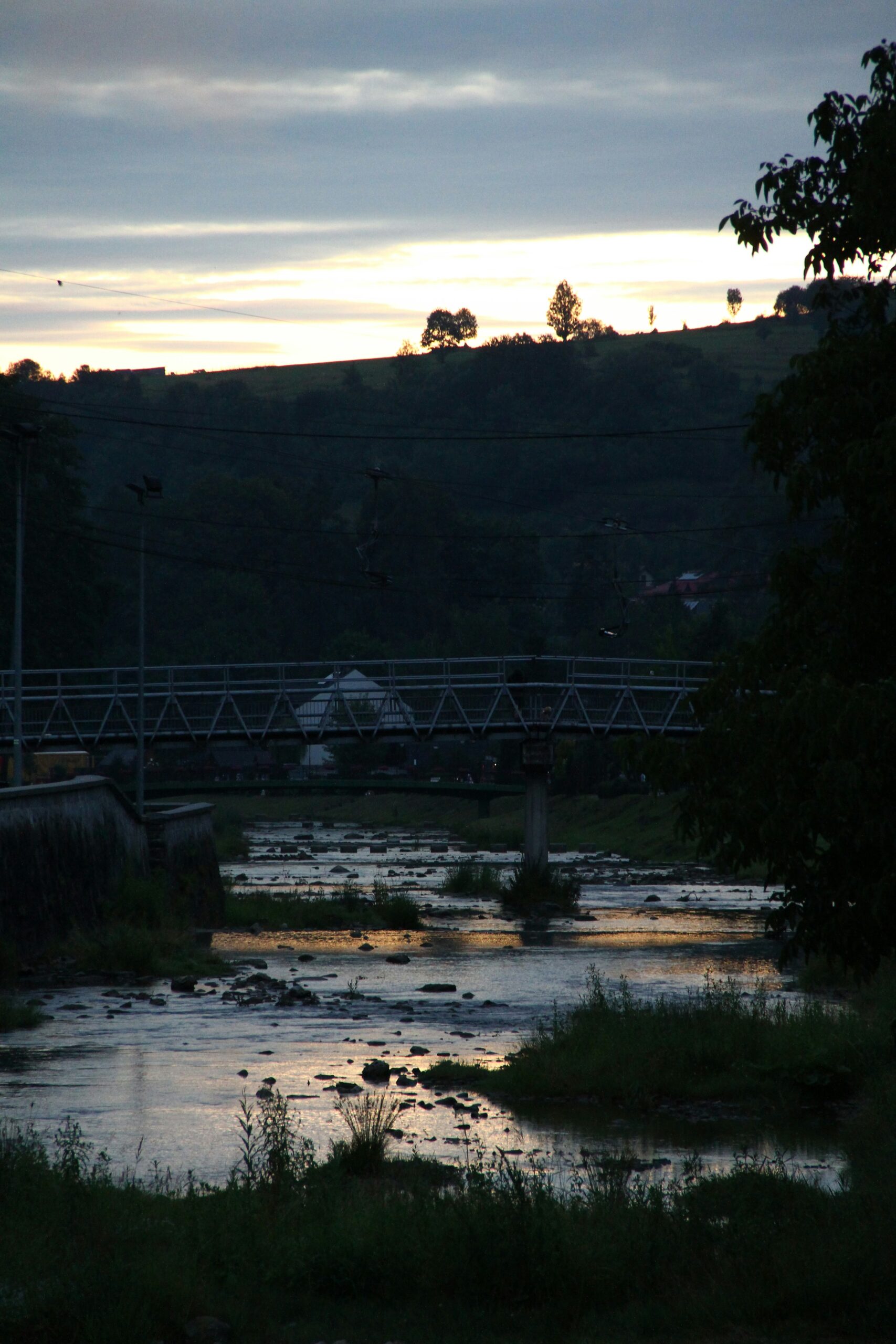 Kamo River at sunset in Kyoto Japan with golden hour light reflecting on water and traditional buildings along riverbank
