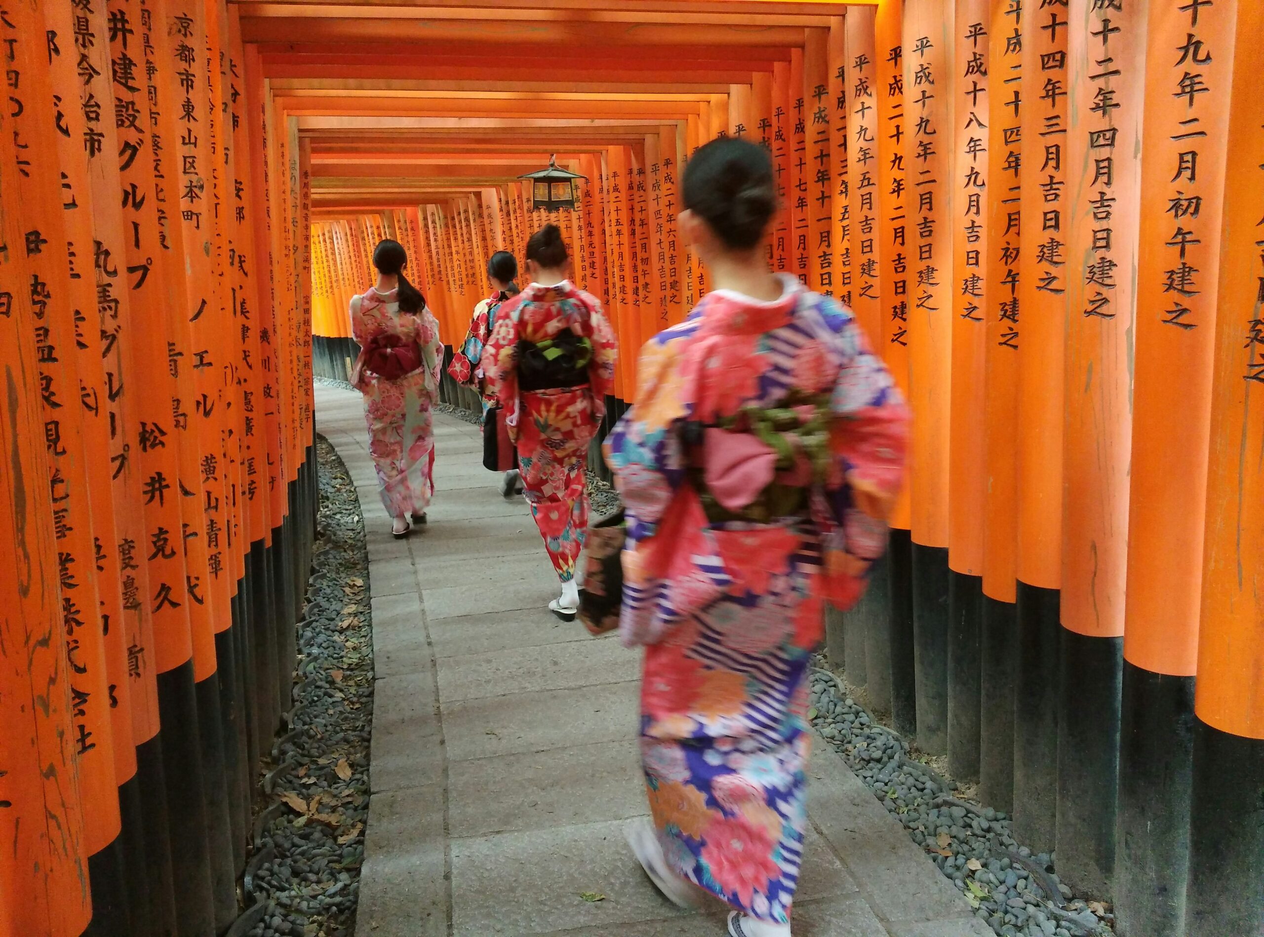 Woman wearing traditional kimono walking through iconic vermilion torii gates at Fushimi Inari Shrine in Kyoto, Japan