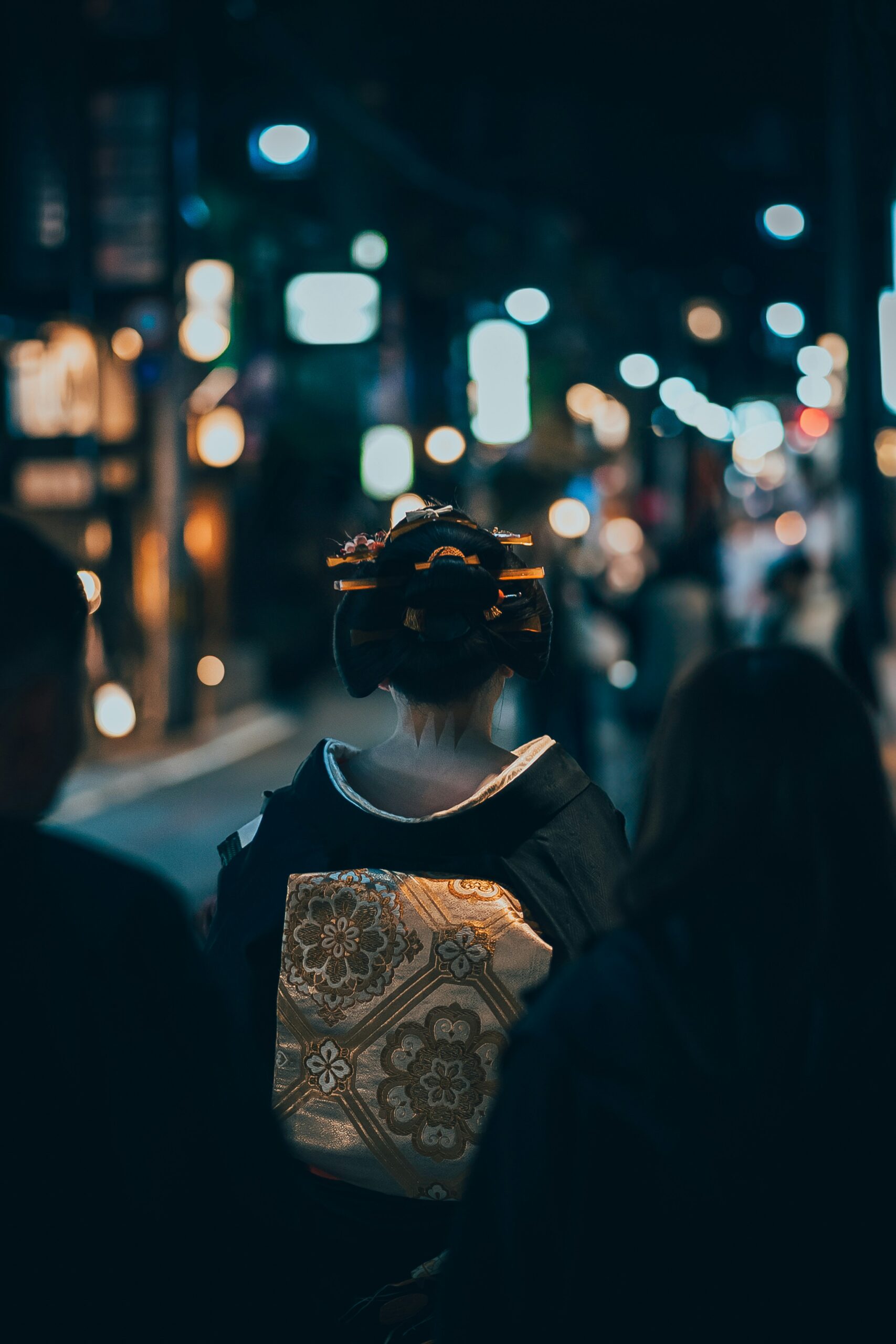 Traditional geisha district Gion in Kyoto at night with red lanterns illuminating historic wooden machiya buildings and kimono-clad visitors