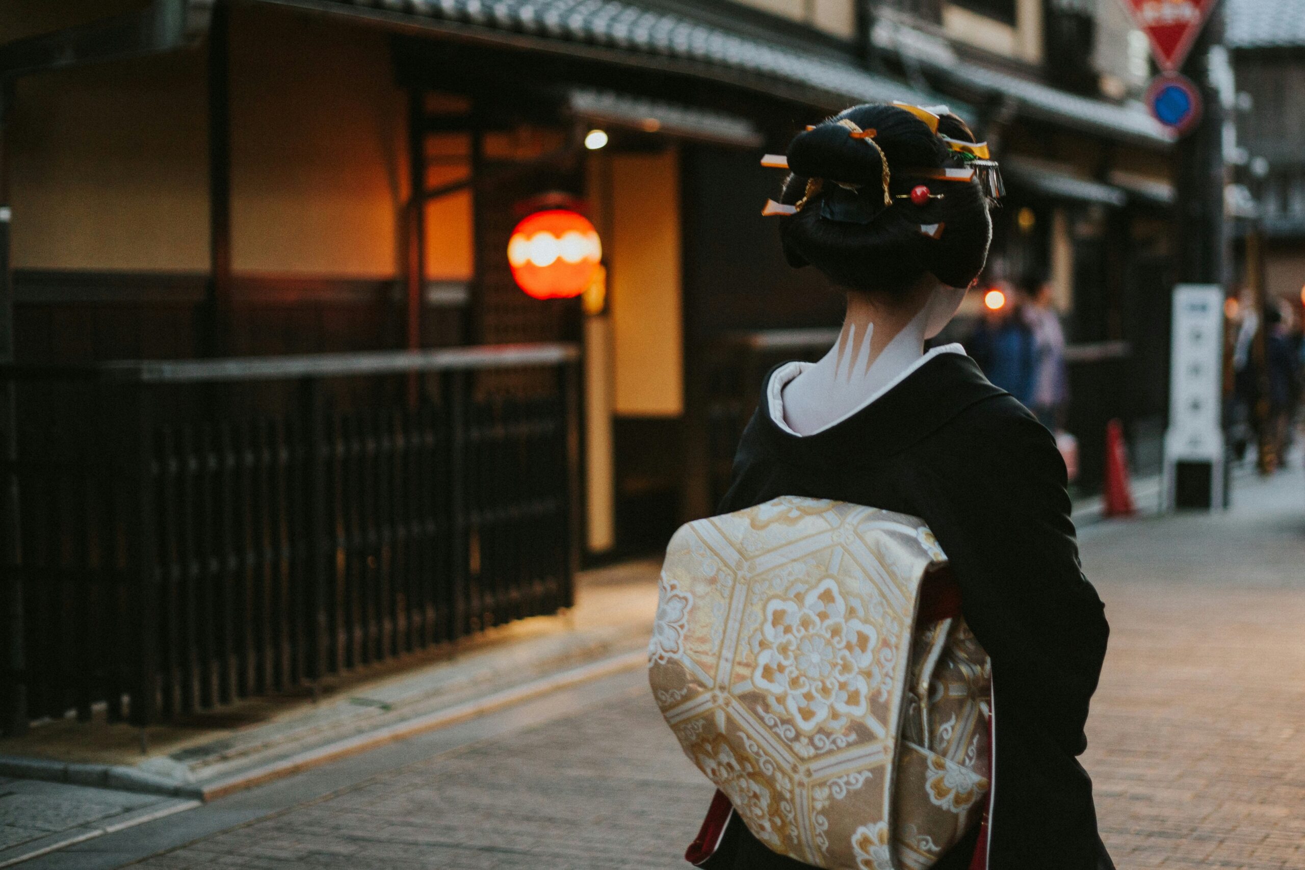Two women wearing elegant traditional Japanese kimonos walking through historic Gion district street in Kyoto