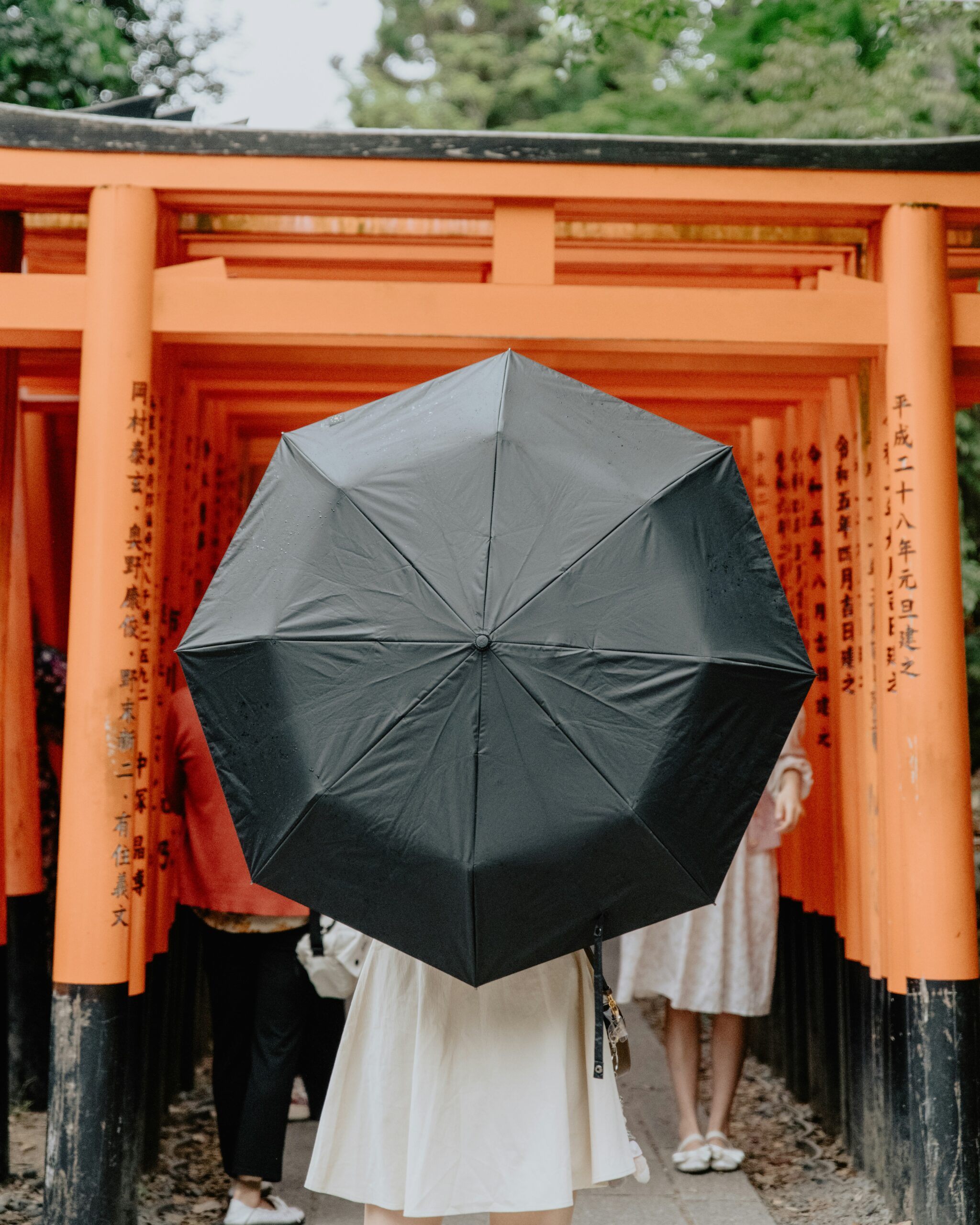 Woman in elegant kimono with wagasa umbrella posing on wet Kyoto pavement showing reflection photography technique