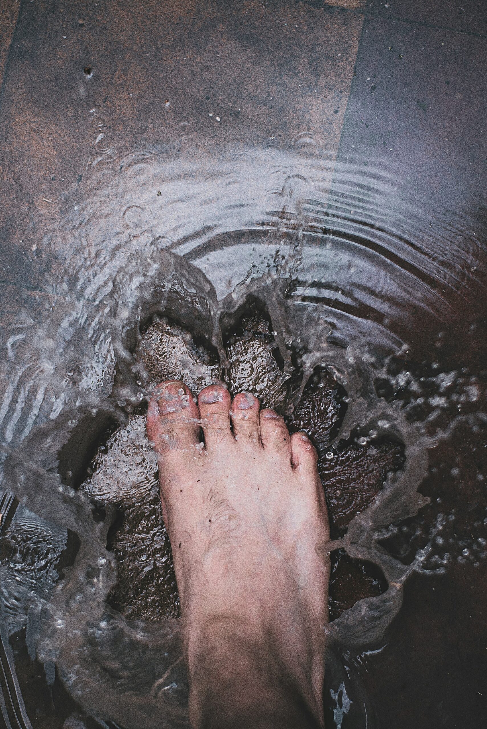 Japanese woman in traditional red and white kimono enjoying ashiyu foot bath at outdoor onsen hot spring spa in Kyoto Japan relaxing her feet in natural thermal mineral water