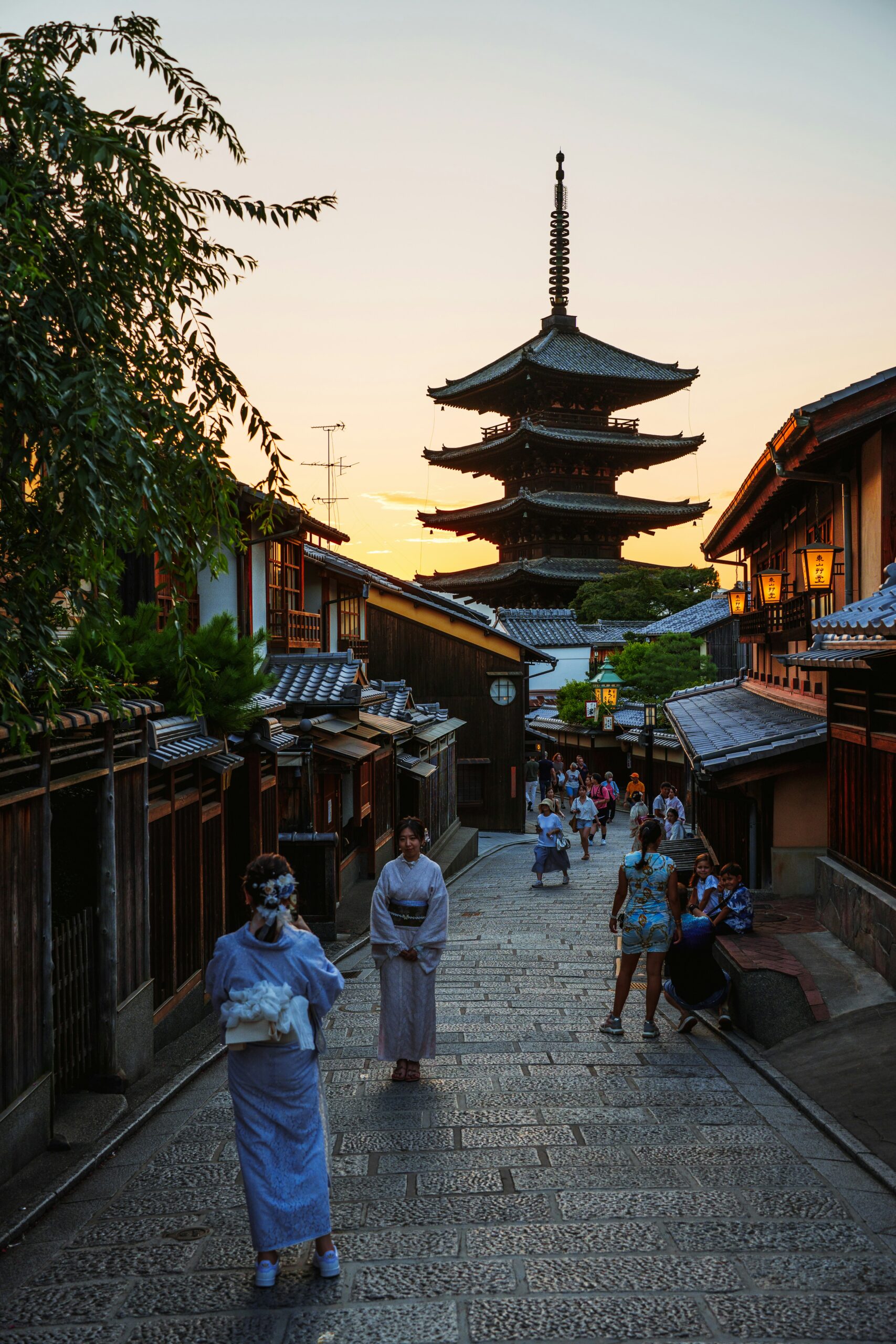 Woman wearing traditional kimono walking on historic Higashiyama street in Kyoto with Yasaka Pagoda in background, showcasing authentic Japanese cultural experience